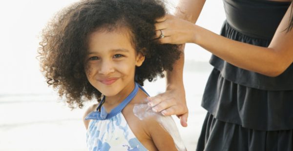 little girl getting sunblock applied to her back